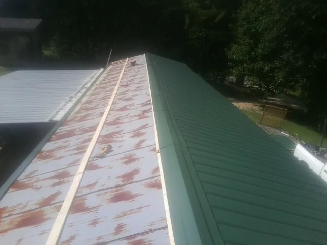 Old rusted panels beside newly installed green metal roofing — Wind Damage Roof Repair by Roofing Brothers in Crawford