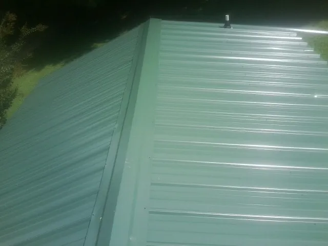 New green metal panels meeting at the ridge of a roof — Flat Roof Repair work by our crew in Crawford