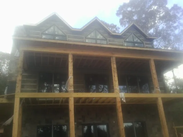 Dormers and porch framing on a large log home under construction — Roof Coating work by our crew in Crawford